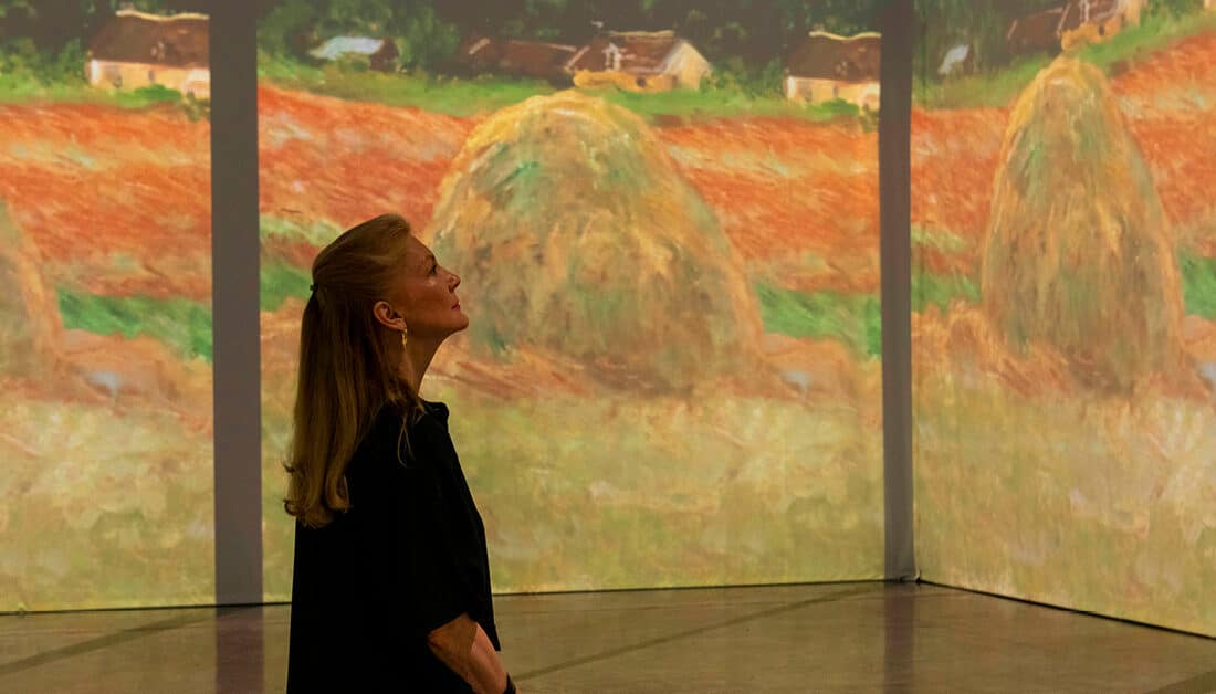 A woman looking at projections of Claude Monet's Haystacks painting